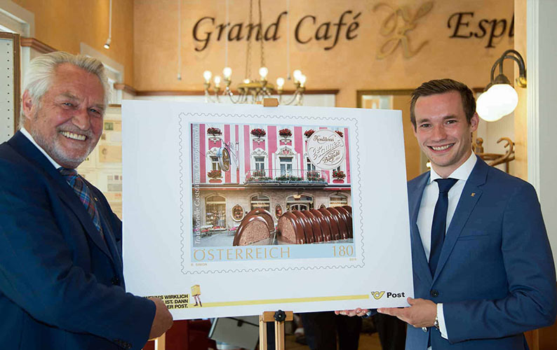 Handover of the Zauner stamp. An enlarged postage stamp on a shelf, with Josef and Philipp Zauner standing next to it.