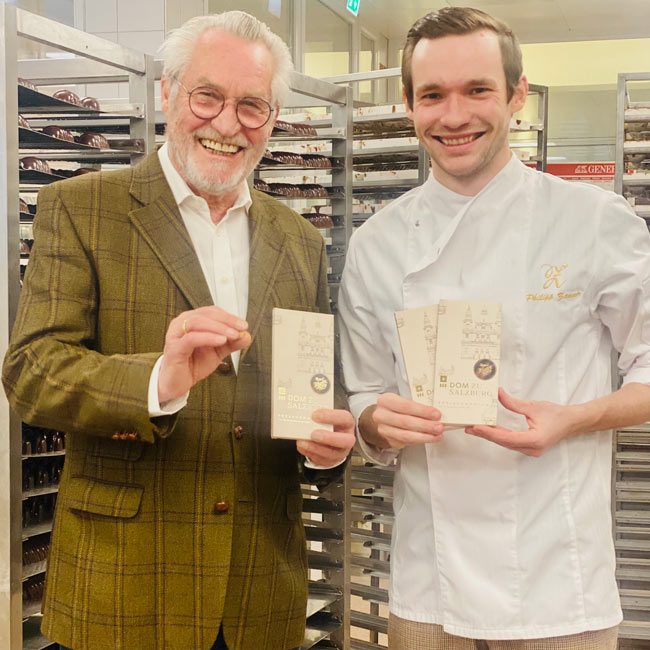 Josef and Philipp Zauner smile into the camera and hold up their creation "Dom Schokolade".