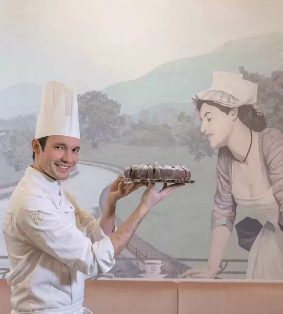 Josef and Philipp Zauner stand back to back, smile into the camera and each hold up a cake.