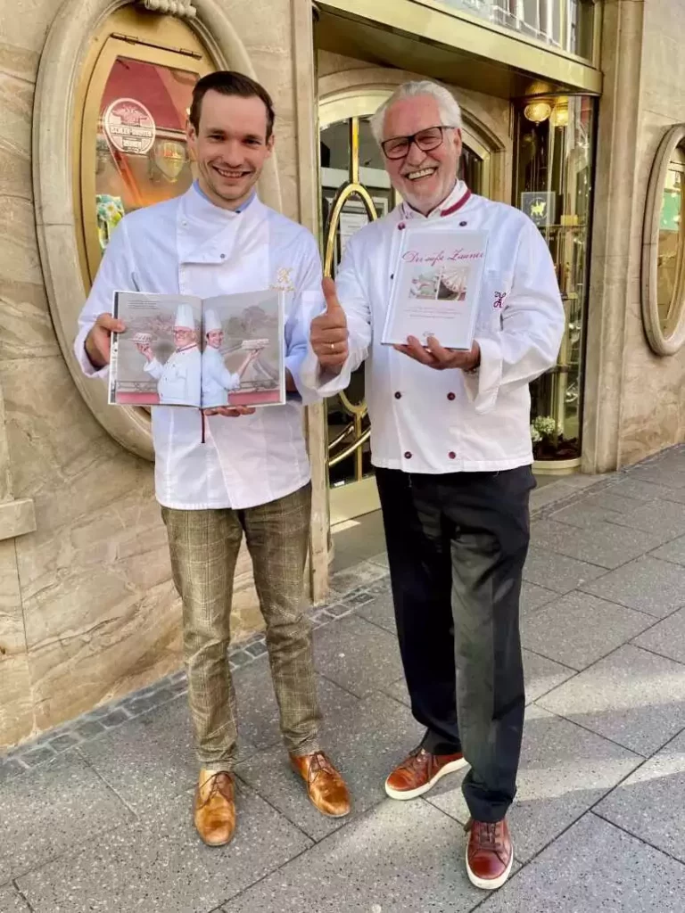 Josef and Philipp Zauner look into the camera smiling. Everyone holds up a copy of the book “The Sweet Zauner”.