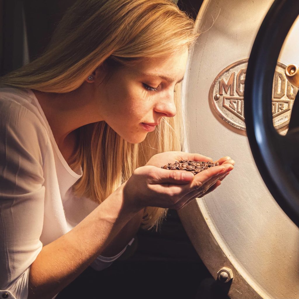 Marlene Drack riecht an Kaffeebohnen in ihren Händen.