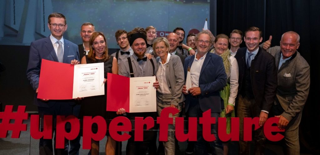 Notos 2021 awards ceremony - a group of people smiles into the camera. In front of it is the writing “#upperfuture”.