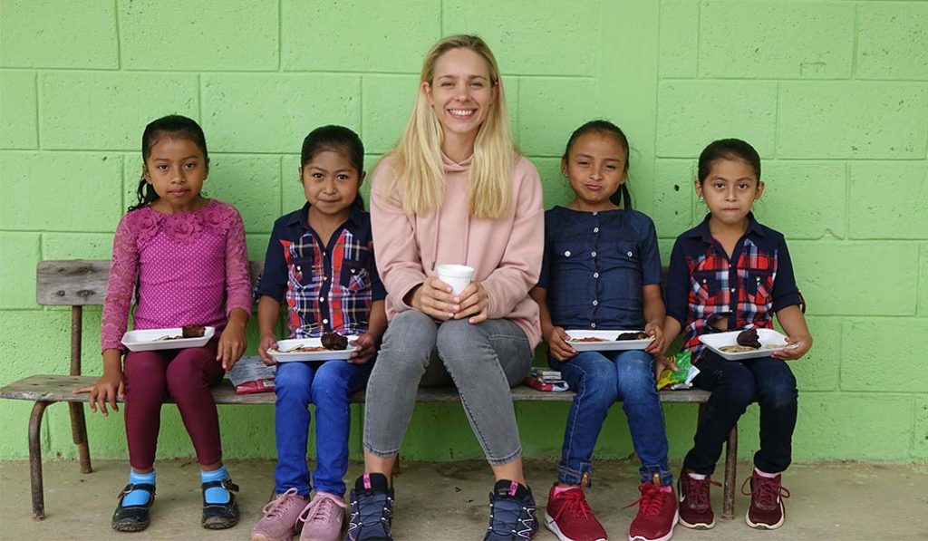 Marlene Drack sitting on a bench with school children.