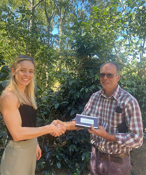 Marlene Drack shakes hands with a coffee farmer and gives him a Zaunerstollen as a gift.