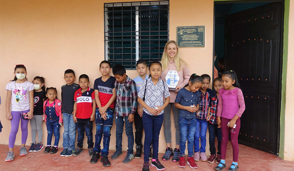 Marlene Drack lined up in front of a wall with school children.