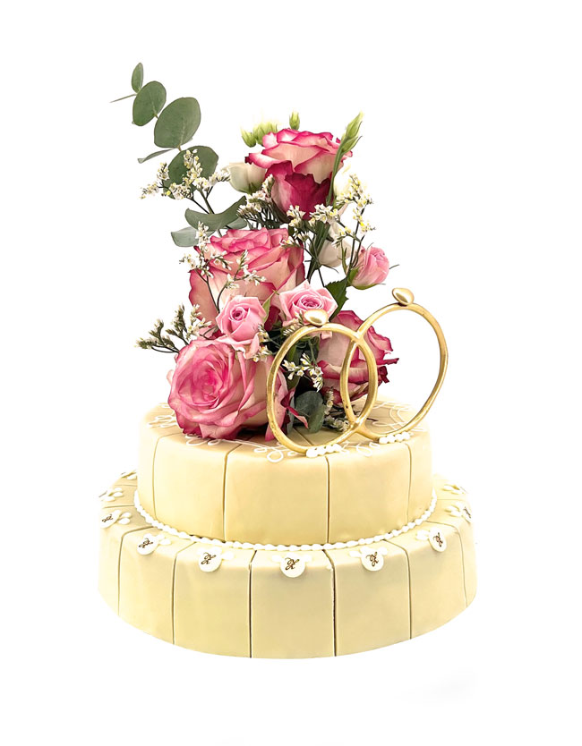 individuelle zweistöckige hellgelbe Torte mit echten Rosen und großen goldenen Dekorringen verziert